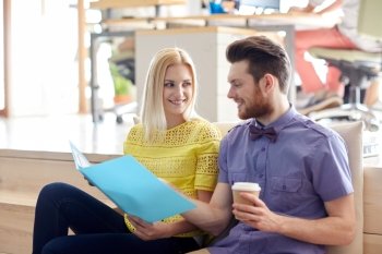 business, startup and  people and concept - happy man and woman with folder  drinking coffee and talking in office