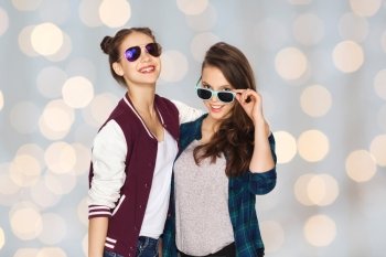 people, friendship, fashion, summer and teens concept - happy smiling pretty teenage girls in sunglasses over holidays lights background