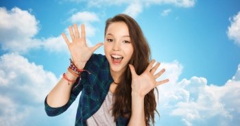 people and teens concept - happy laughing pretty teenage girl showing hands over blue sky and clouds background. happy laughing pretty teenage girl showing hands