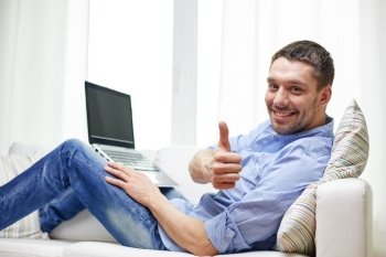 technology, people and lifestyle concept - smiling man working with laptop at home