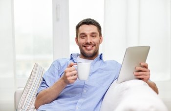 technology, people and lifestyle, distance learning concept - happy man with tablet pc computer drinking coffee or tea at home