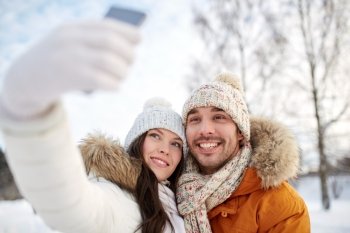 people, season, love, technology and leisure concept - happy couple taking selfie by smartphone over winter background