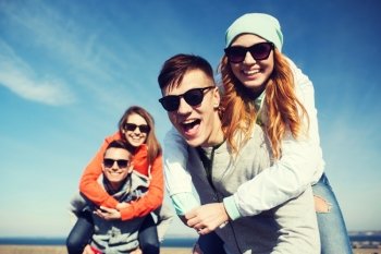 friendship, leisure and people concept - group of happy teenage friends in sunglasses having fun outdoors