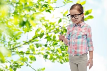 childhood, environment, ecology, discovery and people concept - happy little girl in eyeglasses with magnifying glass over green natural background