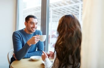 people, communication and dating concept - happy couple drinking tea and coffee at cafe