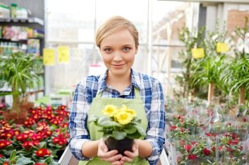 people, gardening and profession concept - happy woman or gardener holding flowers in greenhouse or shop
