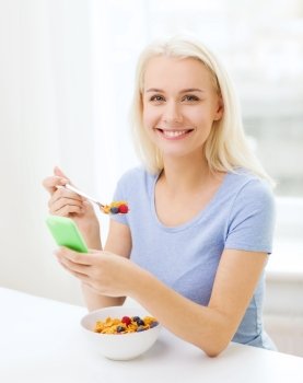 healthy eating, dieting and people concept - smiling young woman with tablet pc computer eating breakfast with smartphone at home