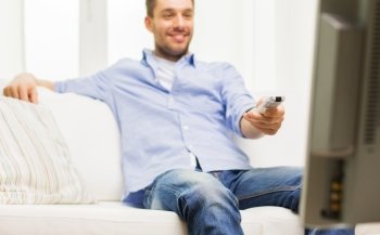 home, people, technology and entertainment concept - close up of man watching tv and changing channels with remote control at home