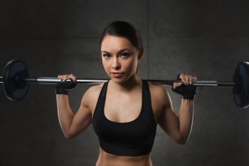 sport, fitness, bodybuilding, weightlifting and people concept - young woman with barbell flexing muscles in gym