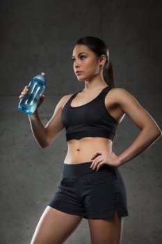 fitness, sport, training, drink and lifestyle concept - woman drinking water from bottle in gym
