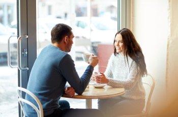 people, communication and dating concept - happy couple drinking tea and coffee at cafe