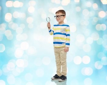 childhood, education, investigation, discovery and people concept - happy little boy in eyeglasses with magnifying glass over blue holidays lights background
