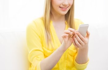 people, technology and leisure concept - close up of young woman texting on smartphone at home