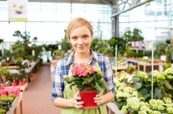 people, gardening and profession concept - happy woman or gardener holding flowers in greenhouse or shop