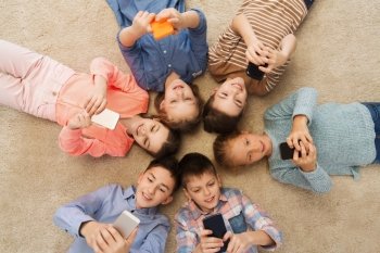 childhood, fashion, friendship and people concept - happy smiling children lying on floor in circle