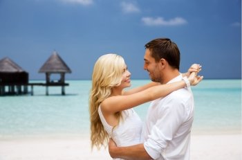 summer holidays, tourism, vacation, travel and dating concept - happy couple having fun at sea side over beach with bungalow background