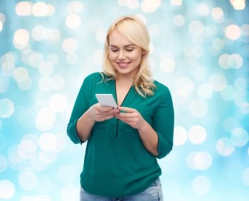 people, technology, communication and leisure concept - happy young woman with smartphone texting message over blue holidays lights background