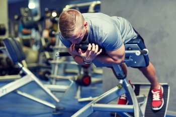 sport, fitness, bodybuilding, lifestyle and people concept - young man flexing back and abdominal muscles on bench in gym