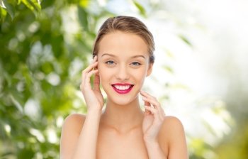 beauty, people and health concept - smiling young woman face with pink lipstick on lips and shoulders over green natural background