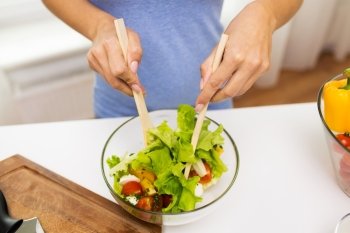 healthy eating, vegetarian food, dieting and people concept - close up of young woman cooking vegetable salad at home