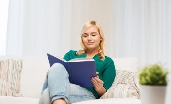 leisure, literature and people concept - smiling woman reading book at home