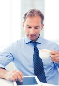 smiling businessman with tablet pc drinking coffee in office. businessman with tablet pc and coffee in office