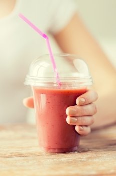 healthy eating, diet and people concept - close up of woman holding plastic cup with juice or smoothie