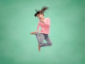 school, education, childhood, freedom and people concept - happy little girl jumping in air over green school chalk board background