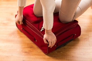 summer vacation, travel, tourism and objects concept - close up of woman packing and zipping travel bag for vacation
