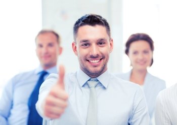 attractive businessman in office showign thumbs up. businessman in office showign thumbs up