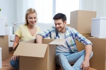 moving, people, repair and real estate concept - smiling couple looking into big cardboard box at new home