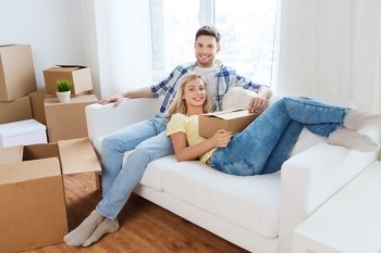 moving, people, repair and real estate concept - happy couple with big cardboard boxes on sofa at new home