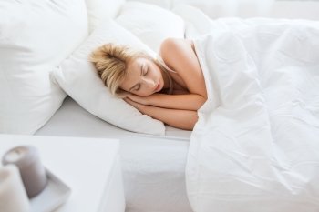 rest, comfort and people concept - young woman sleeping in bed at home bedroom