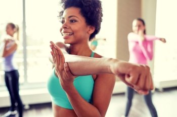 fitness, sport, dance, people  and lifestyle concept - close up of smiling african american woman with group of women dancing zumba in gym or studio