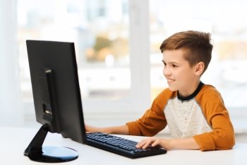 leisure, education, children, technology and people concept - smiling boy with computer at home