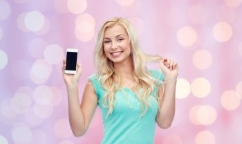 emotions, expressions, technology and people concept - smiling young woman or teenage girl showing blank smartphone screen over pink holidays lights background