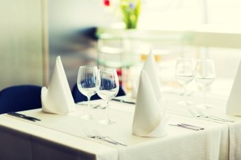 objects, dinnerware and holidays concept - close up of table setting with glasses, napkins and cutlery