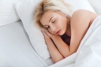 rest, comfort and people concept - young woman sleeping in bed at home bedroom