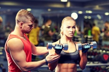 fitness, sport, bodybuilding and weightlifting concept - young woman and personal trainer with dumbbells flexing muscles in gym