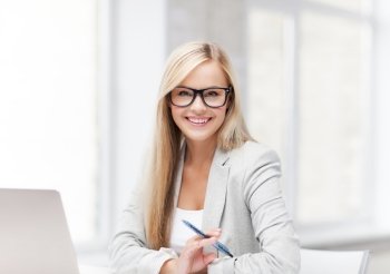 indoor picture of smiling woman with laptop and pen