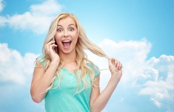 emotions, expressions, technology and people concept - smiling young woman or teenage girl calling on smartphone over blue sky and clouds background