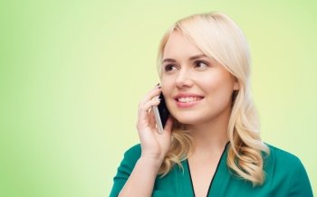 people, technology, communication and leisure concept - happy young woman calling on smartphone over green natural background
