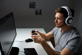technology, gaming, entertainment, let&#39;s play and people concept - young man in headset with controller gamepad playing computer game at home and streaming playthrough or walkthrough video