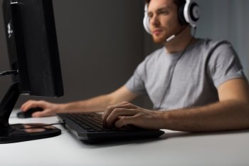 technology, gaming, entertainment, let&#39;s play and people concept - close up of young man in headset with pc computer playing game at home and streaming playthrough or walkthrough video