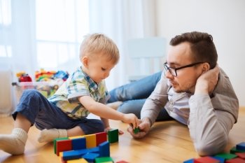 family, childhood, creativity, activity and people concept - happy father and little son playing with toy blocks at home