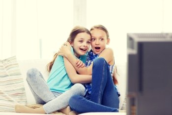 people, children, television, friends and friendship concept - two scared little girls watching horror on tv at home