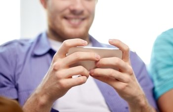 friendship, technology and people concept - close up of happy man with smartphone texting or playing games at home