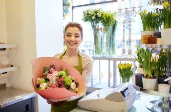 people, business, sale and floristry concept - happy smiling florist woman holding bunch of flowers wrapped into paper at flower shop