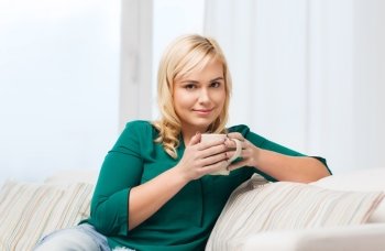 people and leisure concept - happy young woman with cup of tea or coffee at home. happy woman  with cup of tea or coffee at home