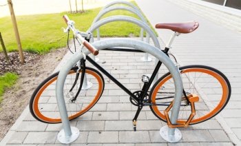 transport, storage, security and safety concept - close up of fixed gear bicycle locked at street parking outdoors